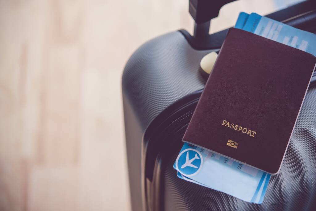 Passeport posé sur une valise avec carte d’embarquement, symbole du départ vers une nouvelle vie.
