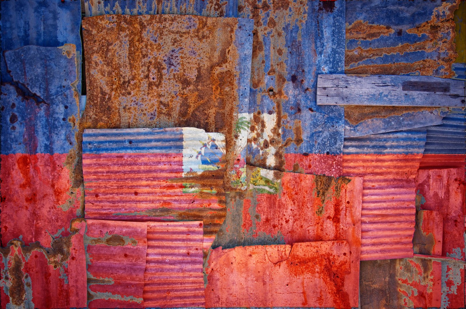 Drapeau d’Haïti peint sur des tôles rouillées, symbolisant les cicatrices laissées par la dette coloniale imposée par la France