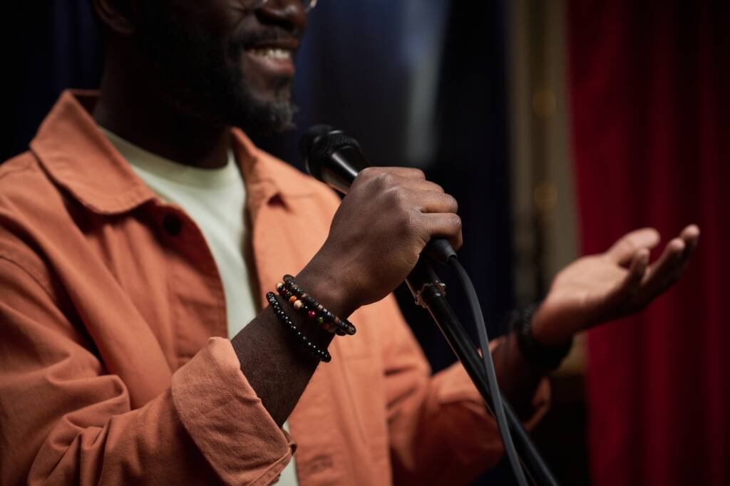 Homme noir s’exprimant avec assurance au micro, illustrant la richesse de l’identité et de l’accent
