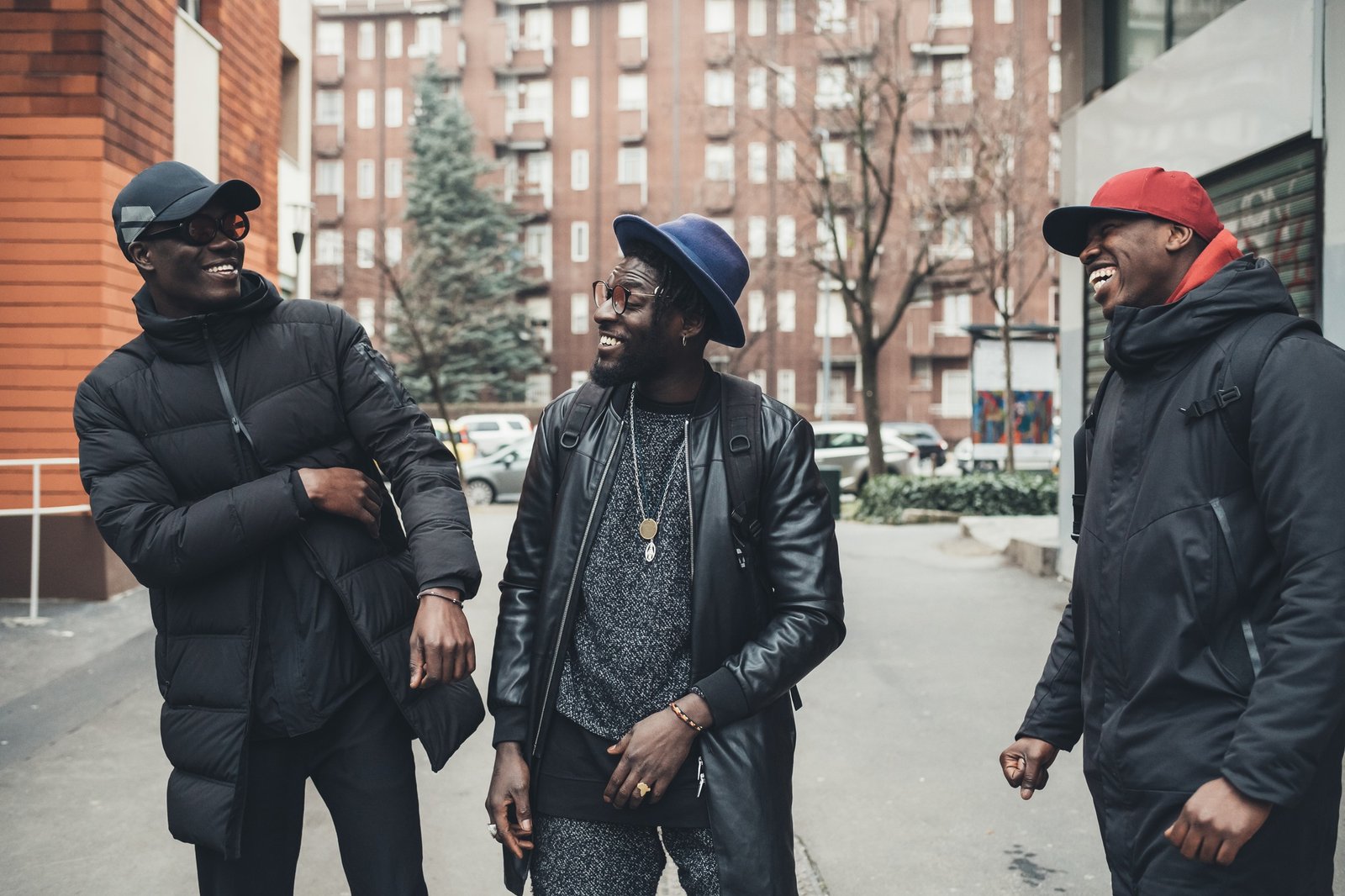Trois hommes noirs souriants discutant dans la rue, symbolisant la diversité des accents et des identités culturelles