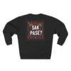 Sweatshirt noir avec l’inscription “SAK PASE?” en blanc et rouge, entourée de motifs haïtiens traditionnels. Design inspiré de la culture créole et de l’article de blog sur la salutation haïtienne de Anprent Berwin.