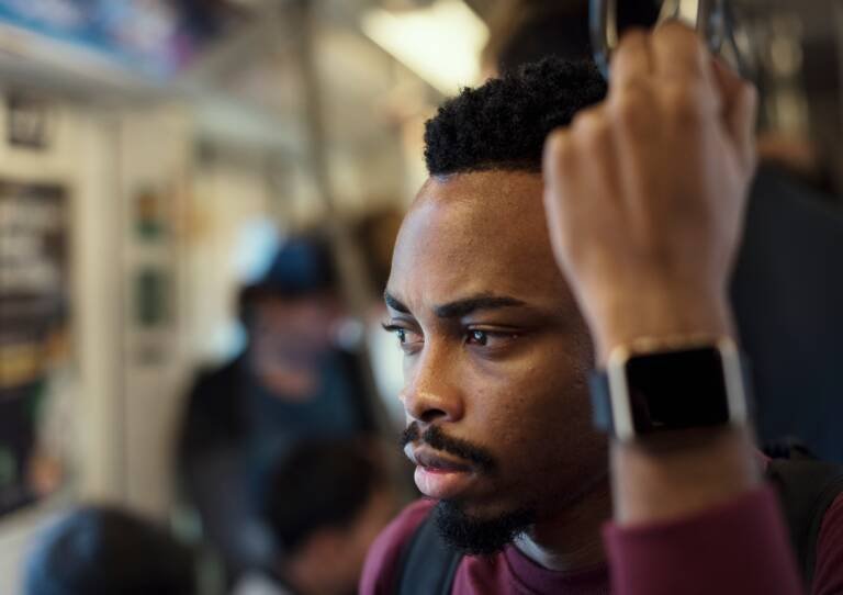 Homme noir pensif dans un train, regardant au loin, illustrant l’introspection et la résonance culturelle de l’expression haïtienne “Sak pase?”